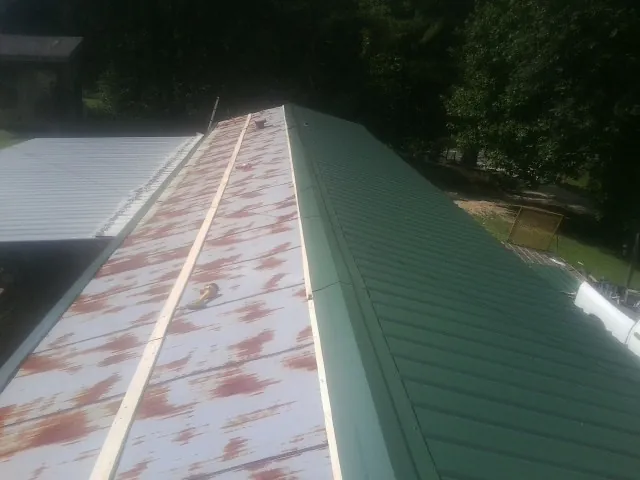 Old rusted panels beside newly installed green metal roofing — Wind Damage Roof Repair by Roofing Brothers in Mooresville