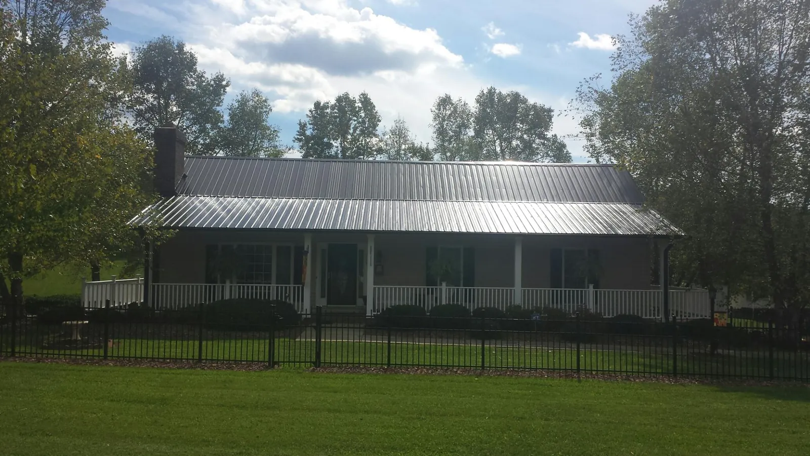 Gray metal roof on a brick ranch with a full width front porch — Gutter Guard Installation work by our crew in Mooresville