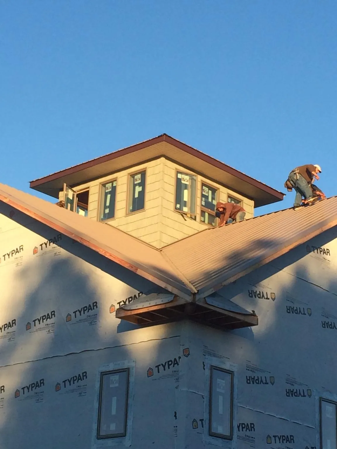 Roofers working around a rooftop cupola on a new metal roof at sunset — Roof Waterproofing in Mooresville by Roofing Brothers
